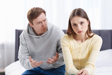Photo of Woman and man having quarrel on bed at home