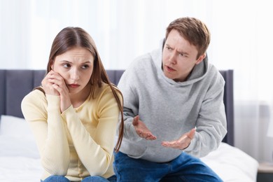 Photo of Woman and man having quarrel on bed at home