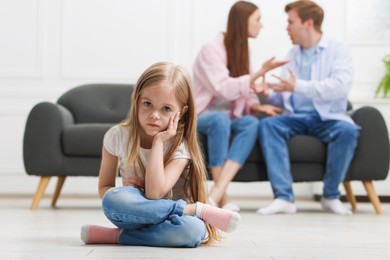 Photo of Upset little girl and her parents fighting at home, selective focus