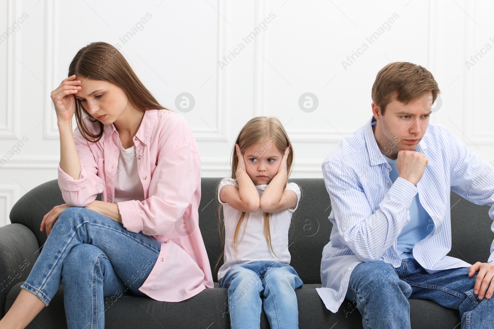 Upset little girl and her parents fighting on sofa at home Photo of Upset little girl and her parents fighting on sofa at home