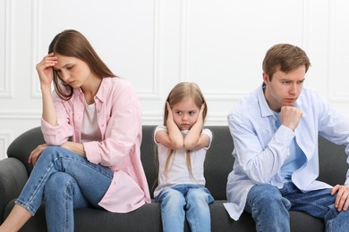 Photo of Upset little girl and her parents fighting on sofa at home