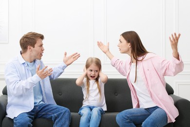Photo of Upset little girl and her parents fighting on sofa at home