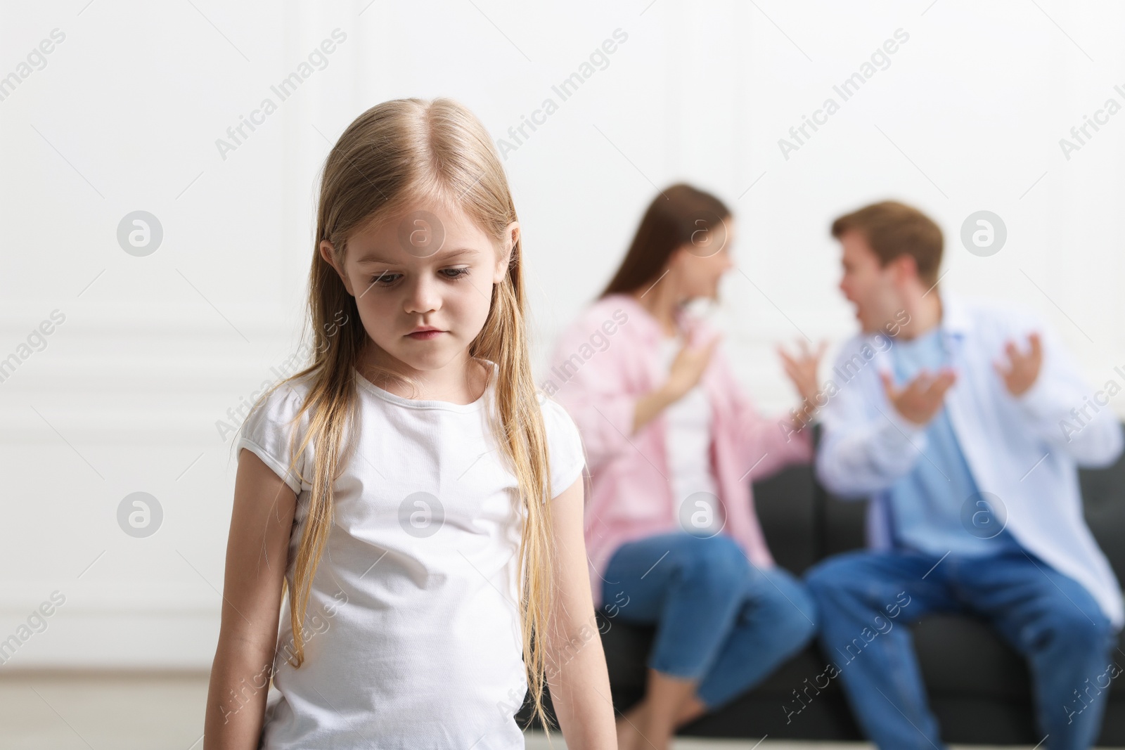 Photo of Upset little girl and her parents fighting at home, selective focus