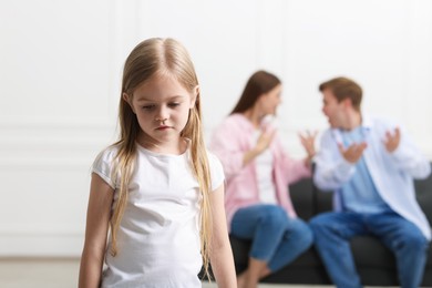 Photo of Upset little girl and her parents fighting at home, selective focus