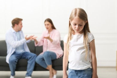 Photo of Upset little girl and her parents fighting at home, selective focus