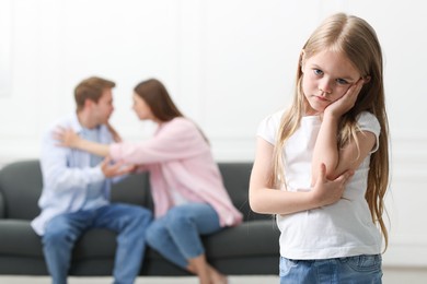 Photo of Upset little girl and her parents fighting at home, selective focus