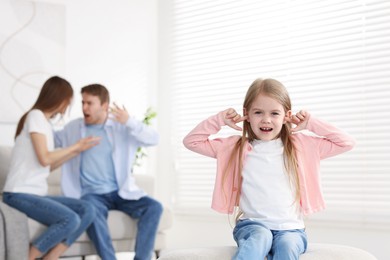 Photo of Upset little girl and her parents fighting at home, selective focus