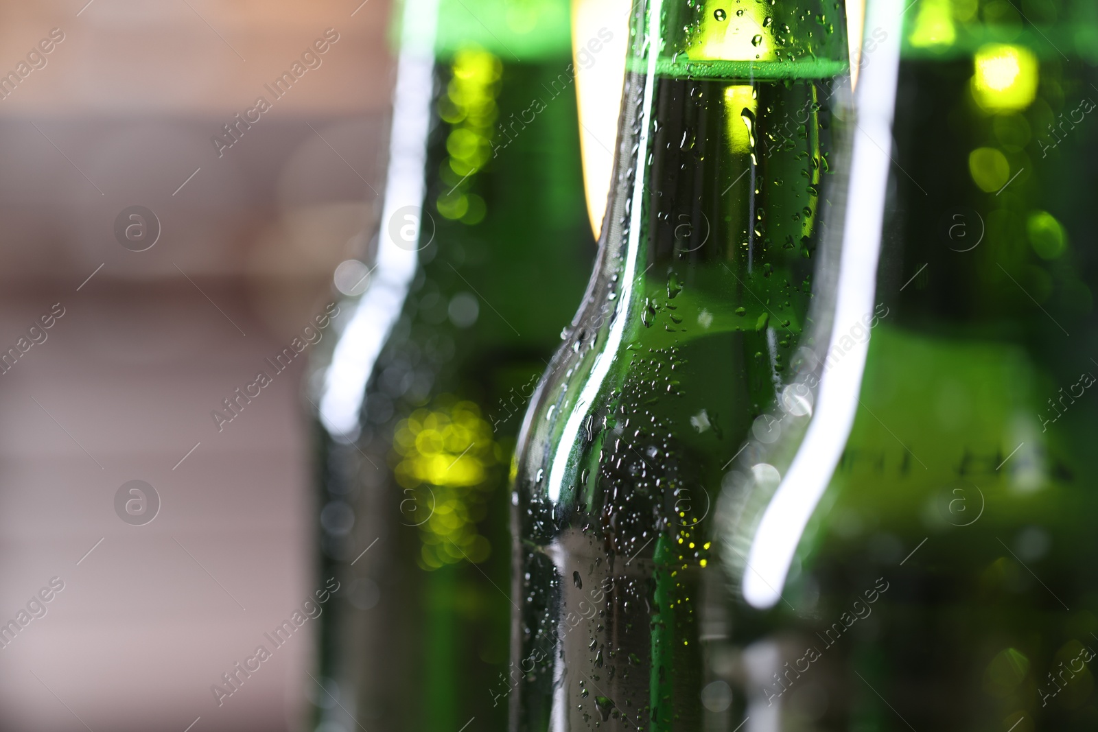 Bottles of beer on blurred grey background, macro view Photo of Bottles of beer on blurred grey background, macro view