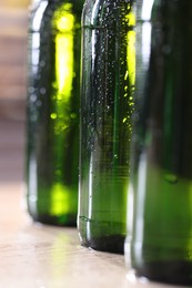 Photo of Bottles of beer on wooden table, macro view