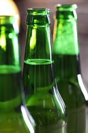 Photo of Bottles of beer on blurred grey background, macro view