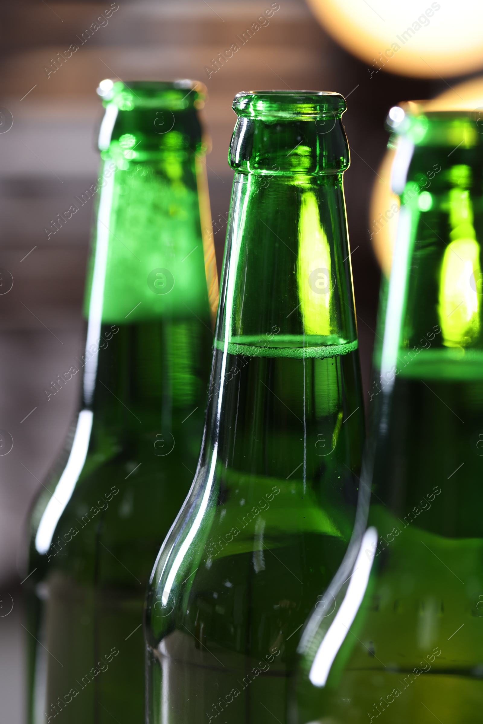 Bottles of beer on blurred grey background, macro view Photo of Bottles of beer on blurred grey background, macro view