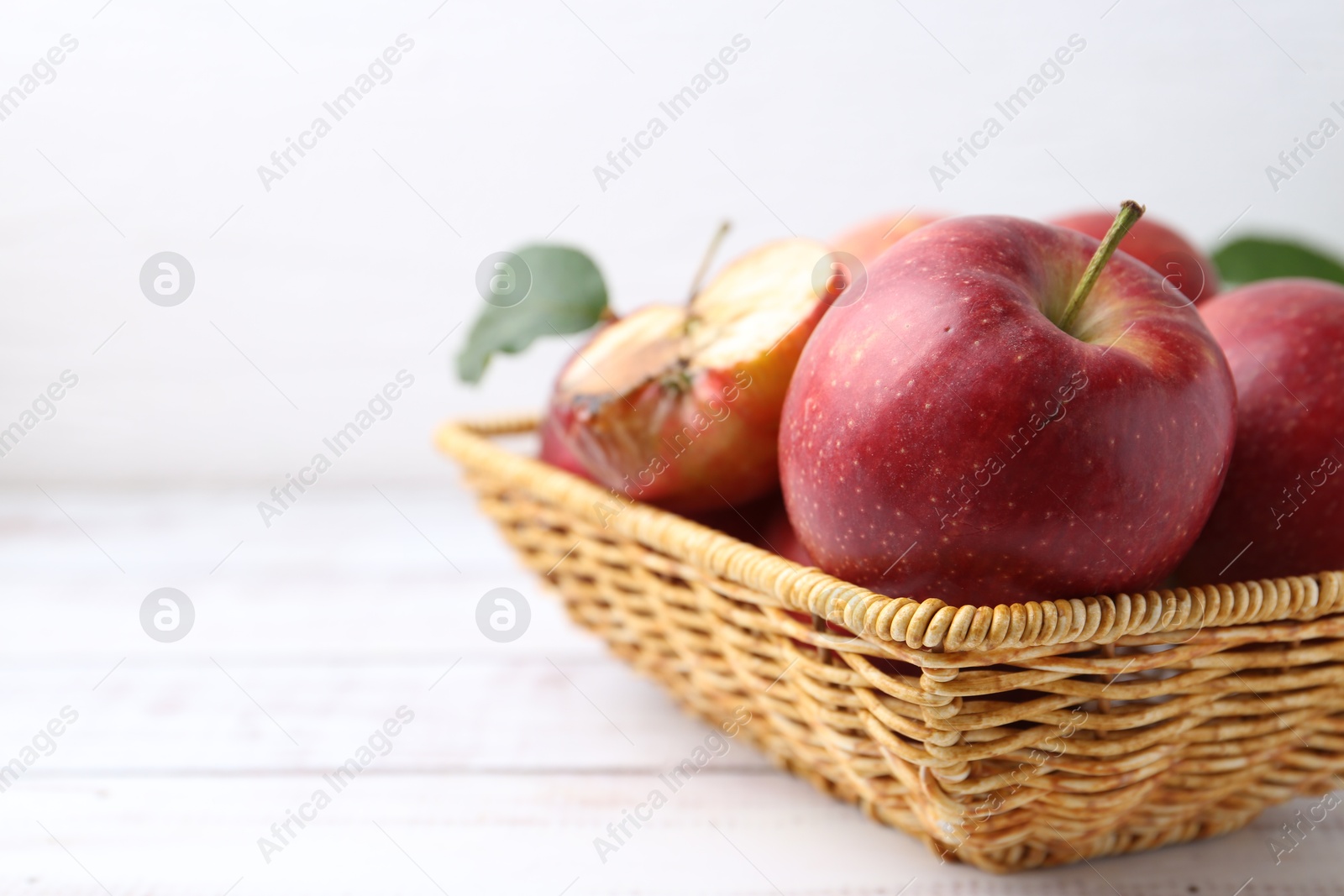 Spoiled apple and good ones in basket on white wooden table, closeup. Space for text Photo of Spoiled apple and good ones in basket on white wooden table, closeup. Space for text