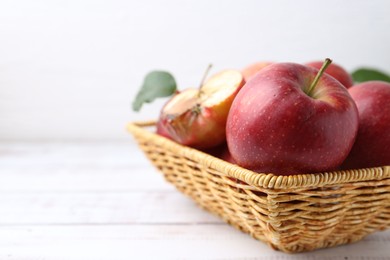 Photo of Spoiled apple and good ones in basket on white wooden table, closeup. Space for text