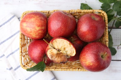 Photo of Spoiled apple and good ones in basket on white wooden table, top view