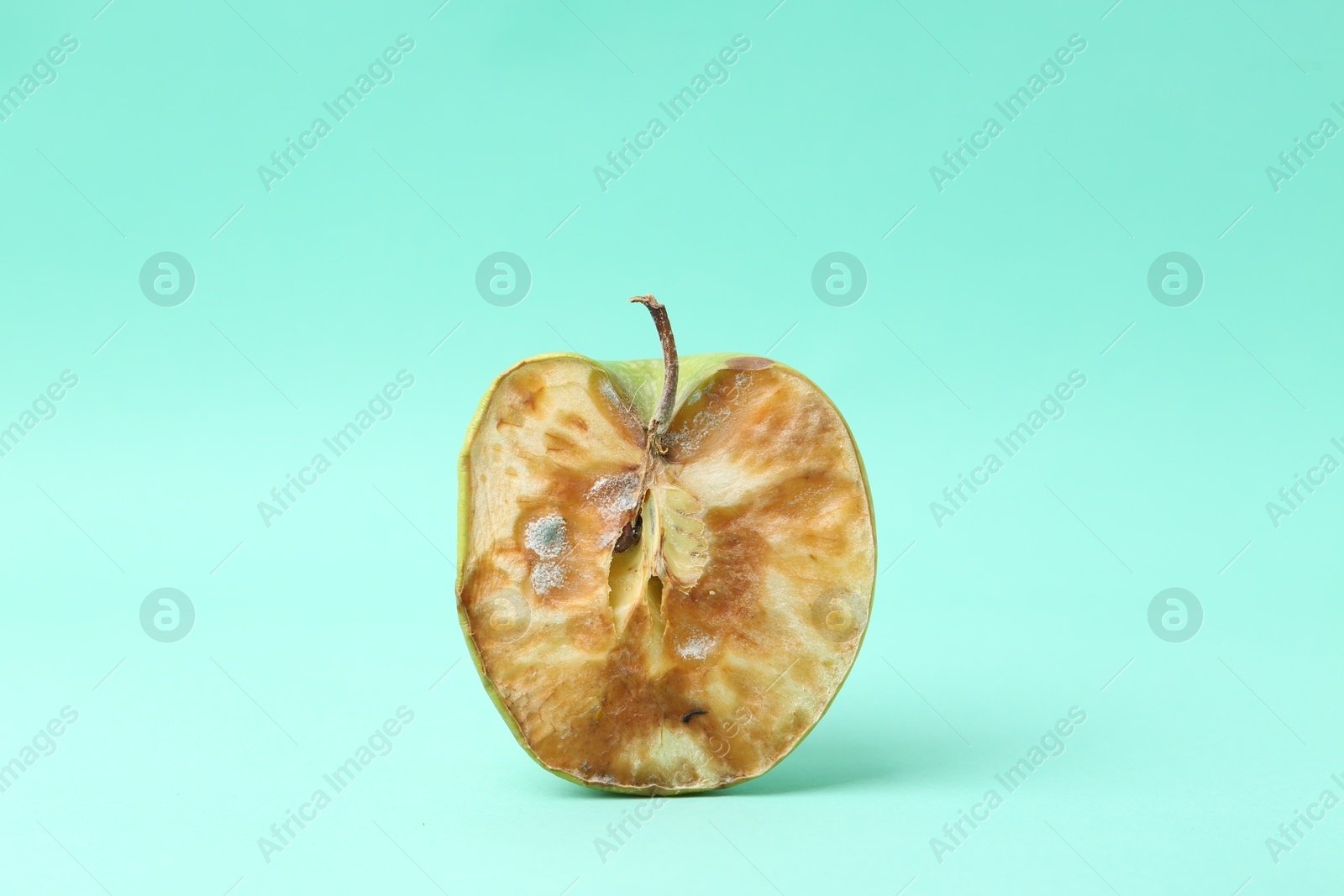 Half of spoiled apple on turquoise background Photo of Half of spoiled apple on turquoise background