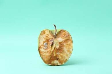 Photo of Half of spoiled apple on turquoise background