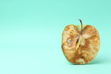 Photo of Half of spoiled apple on turquoise background. Space for text