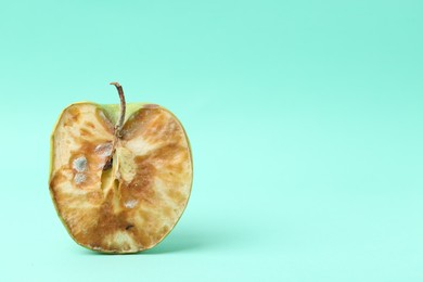 Photo of Half of spoiled apple on turquoise background. Space for text