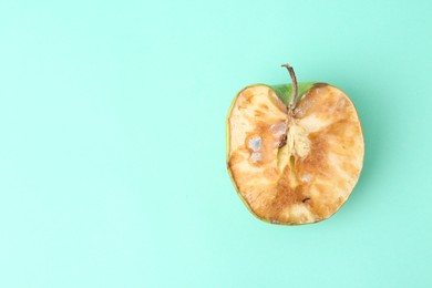 Photo of Half of spoiled apple on turquoise background, top view. Space for text