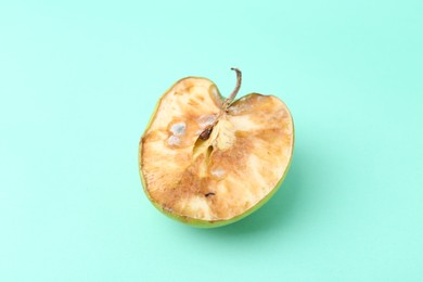 Photo of Half of spoiled apple on turquoise background, top view