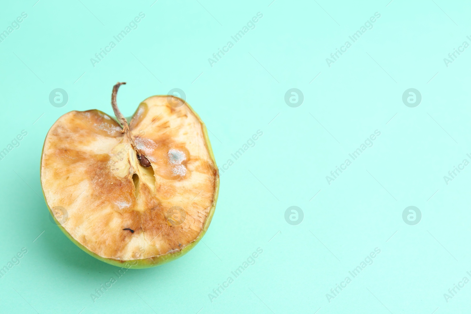 Half of spoiled apple on turquoise background, top view. Space for text Photo of Half of spoiled apple on turquoise background, top view. Space for text