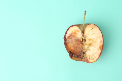 Photo of Half of spoiled apple on turquoise background, top view. Space for text