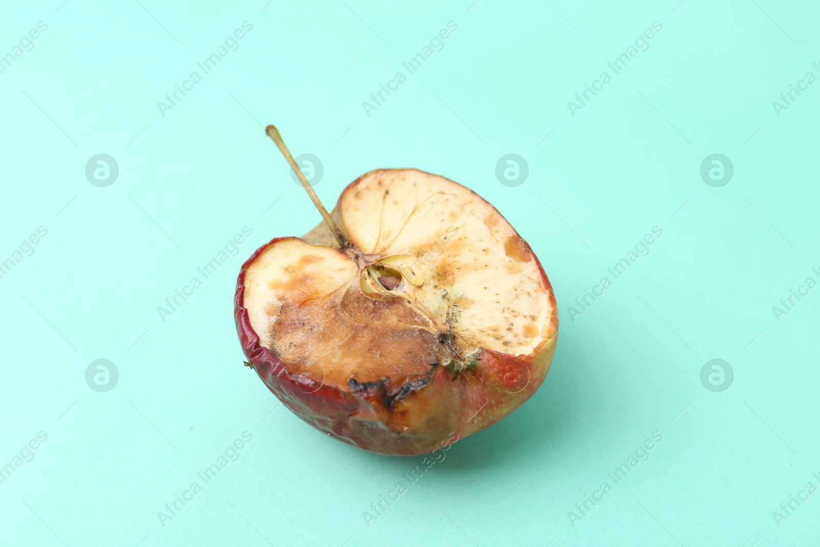 Half of spoiled apple on turquoise background Photo of Half of spoiled apple on turquoise background