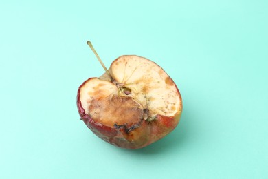 Photo of Half of spoiled apple on turquoise background