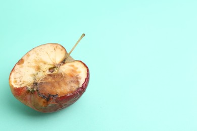 Photo of Half of spoiled apple on turquoise background. Space for text