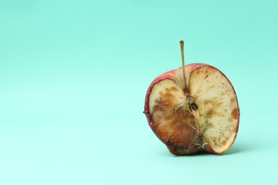 Photo of Half of spoiled apple on turquoise background. Space for text