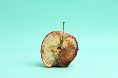 Photo of Half of spoiled apple on turquoise background