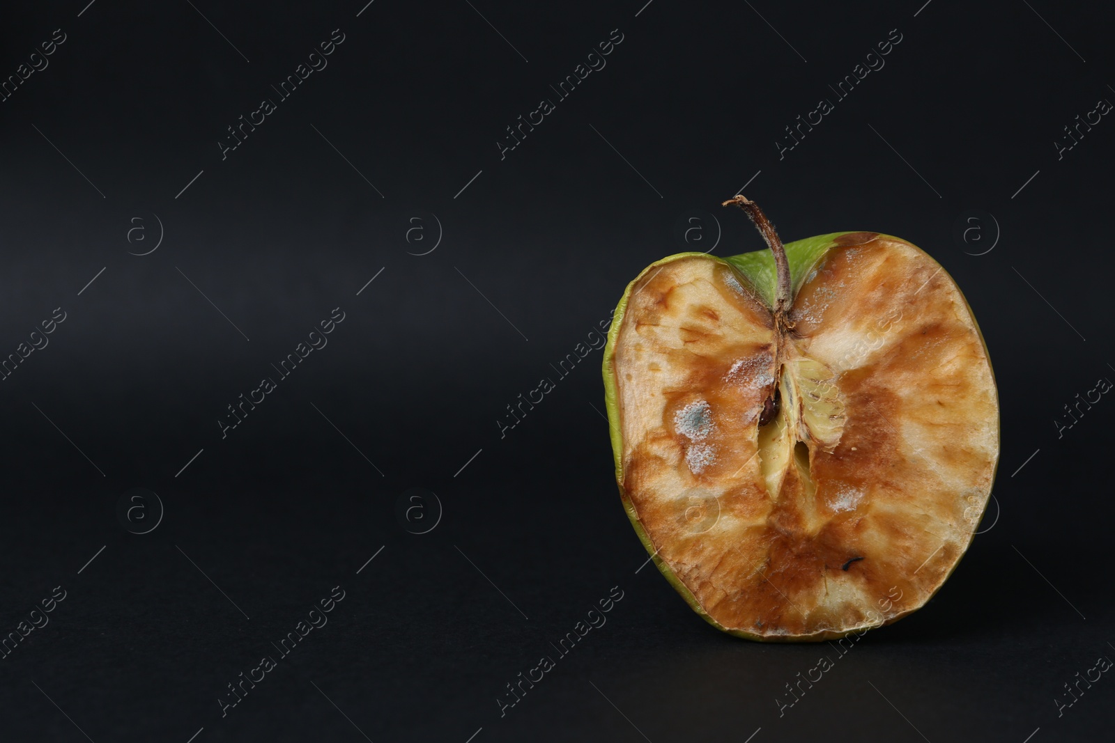 Half of spoiled apple on black background. Space for text Photo of Half of spoiled apple on black background. Space for text