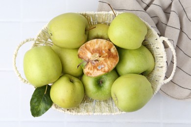 Photo of Spoiled apple and good ones in basket on white table, top view