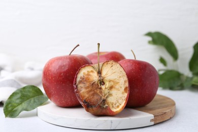 Photo of Spoiled apple and good ones on white table, closeup