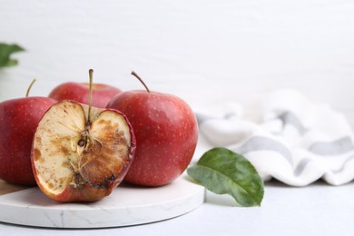Photo of Spoiled apple and good ones on white table, closeup. Space for text