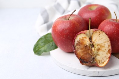 Photo of Spoiled apple and good ones on white table, closeup. Space for text