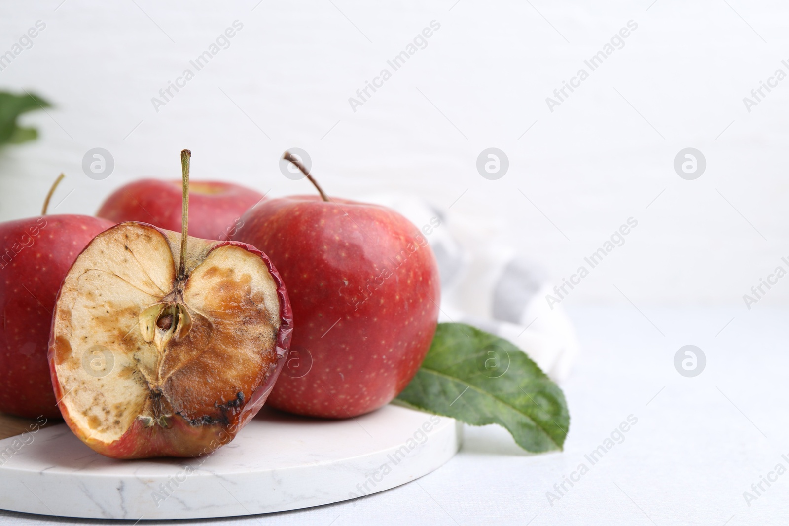Spoiled apple and good ones on white table, closeup. Space for text Photo of Spoiled apple and good ones on white table, closeup. Space for text