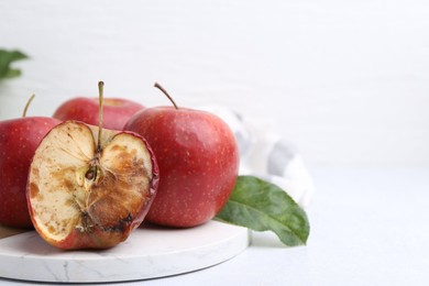 Photo of Spoiled apple and good ones on white table, closeup. Space for text