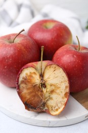 Photo of Spoiled apple and good ones on white table, closeup