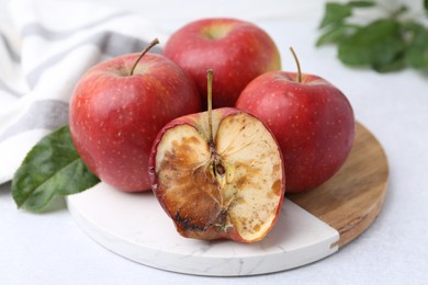 Photo of Spoiled apple and good ones on white table, closeup