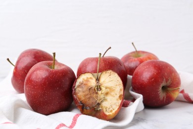 Photo of Spoiled apple and good ones on white table, closeup