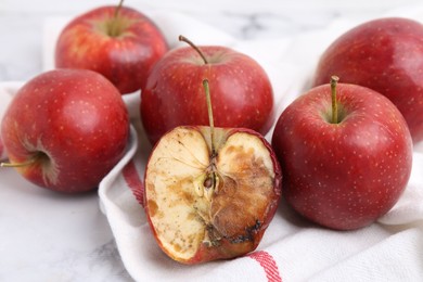 Photo of Spoiled apple and good ones on white table, closeup