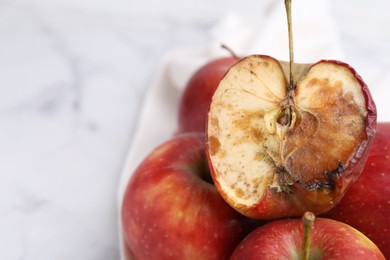 Photo of Spoiled apple and good ones on white table, closeup. Space for text