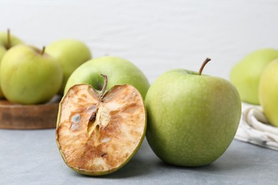 Photo of Spoiled apple and good ones on grey table, closeup