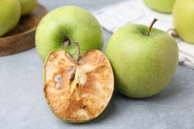 Photo of Spoiled apple and good ones on grey table, closeup