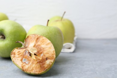 Photo of Spoiled apple and good ones on grey table, closeup. Space for text