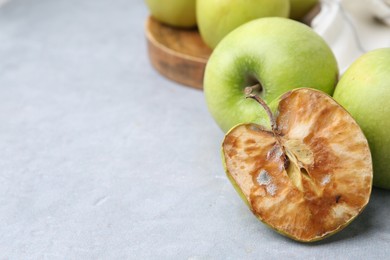 Photo of Spoiled apple and good ones on grey table, closeup. Space for text