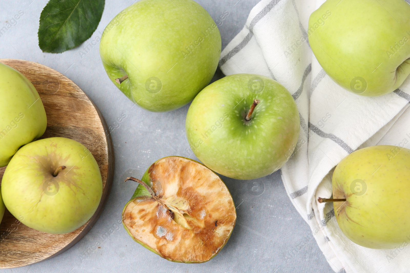 Spoiled apple and good ones on grey table, flat lay Photo of Spoiled apple and good ones on grey table, flat lay