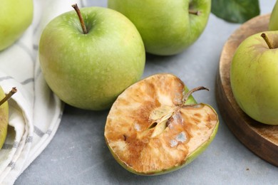 Photo of Spoiled apple and good ones on grey table, closeup