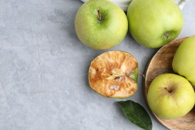 Photo of Spoiled apple and good ones on grey table, flat lay. Space for text